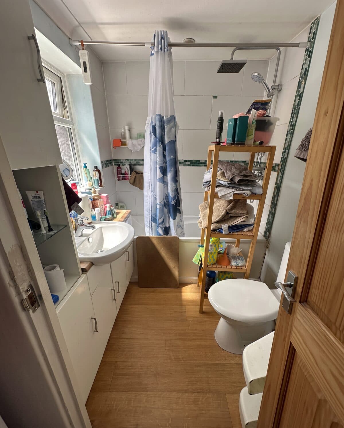 A cramped, dated bathroom with old tiles and a shower curtain