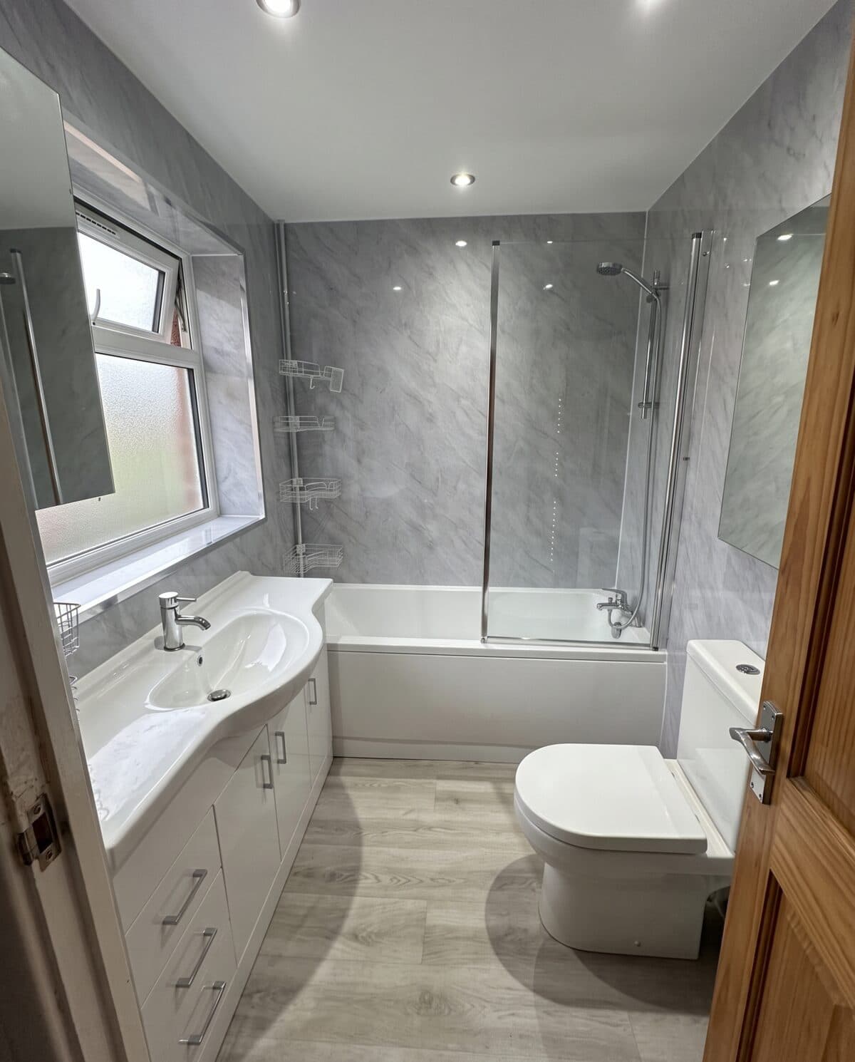 The same bathroom after Greentek fitted grey wall panels, a new bath and a vanity unit